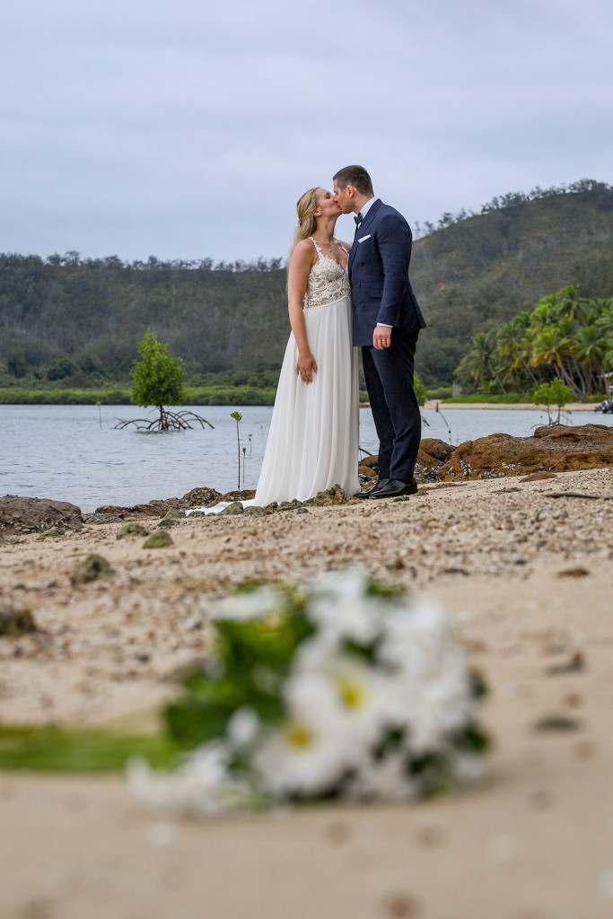 The newlyweds kiss on the shore of the Pacific