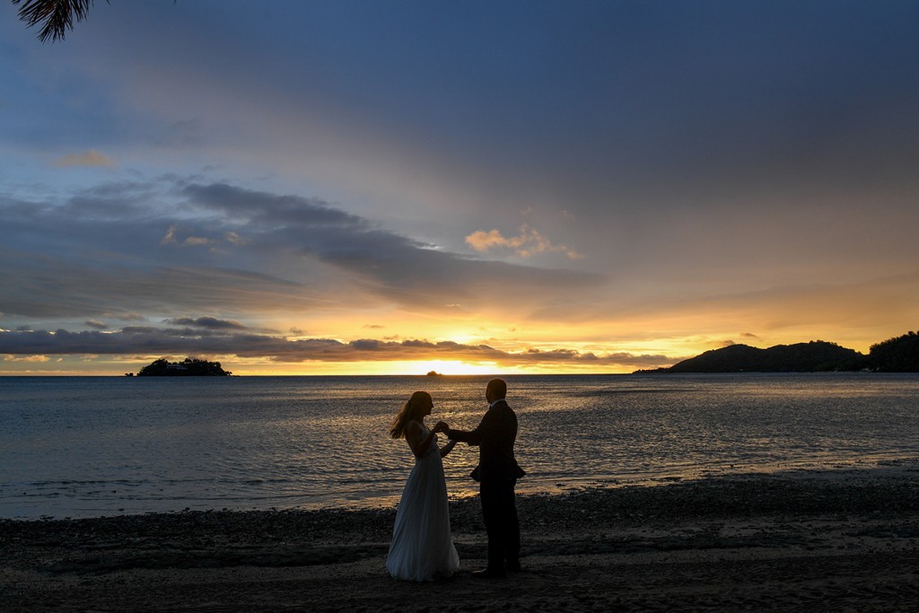 A silhouette of the newlyweds dancing on the shore at sunset