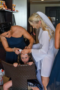 The bride and bridesmaid help curl the flower girl's hair