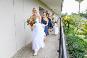 The bride and her bridesmaids form a procession as they walk out of the hotel room