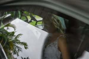 Palm trees reflect off the car window with the stunning bride in the background
