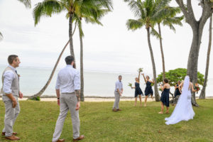 The bridal party plays and has fun under the towering Fiji palm