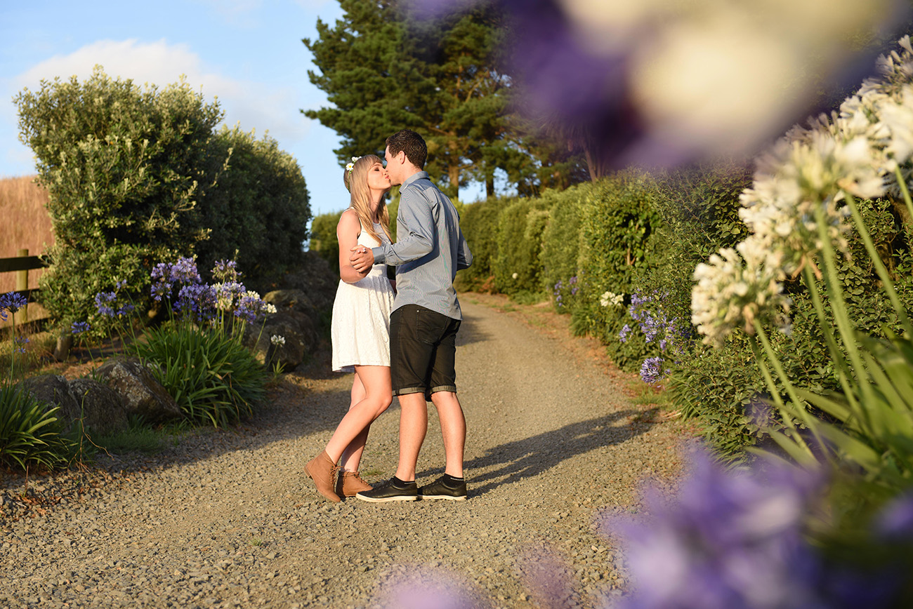 The couple kiss on a lone country road Summer Country Engagement photo shoot Pukekokhe Auckland Photographer Anais Chaine