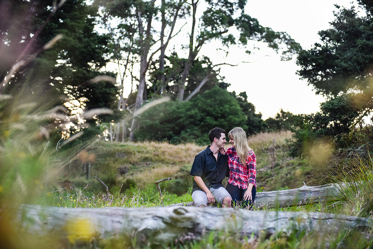 A peek of the couple sitting on a fallen tree in the creek Summer Country Engagement