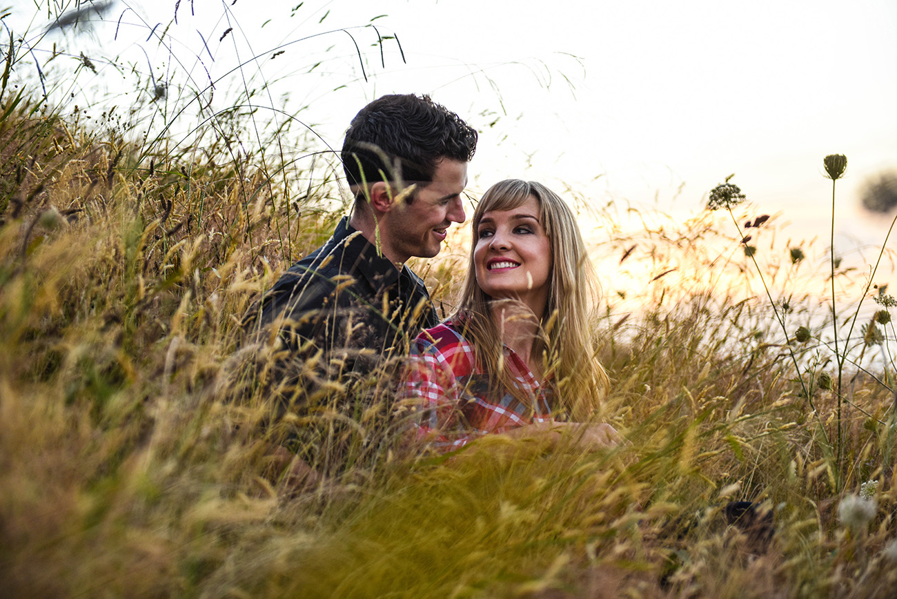 The loving couple gaze at each other hidden in the depth of grass Summer Country Engagement photo shoot Pukekokhe Auckland Photographer Anais Chaine