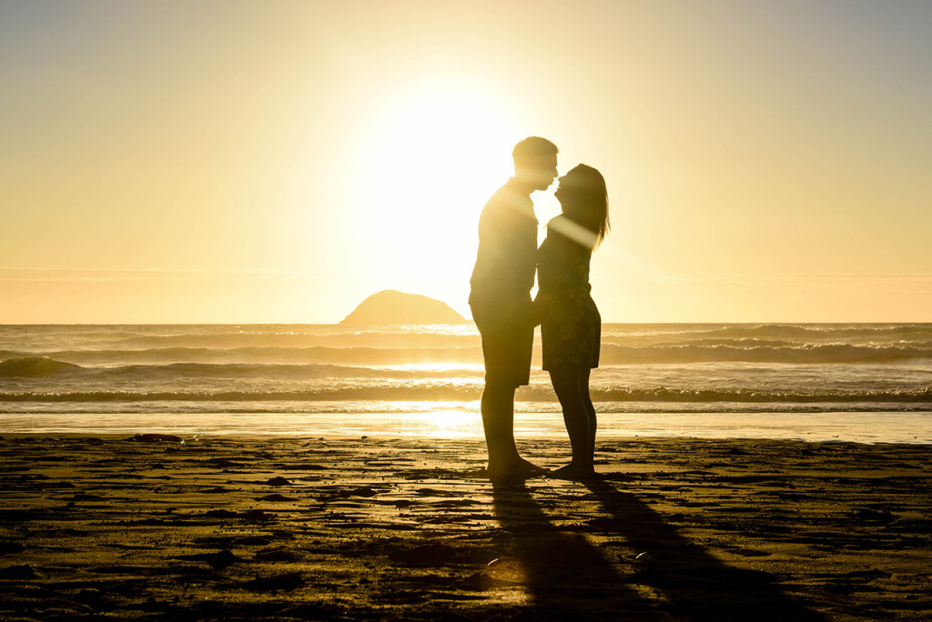 couple kissing silhouette with sun and sea behind