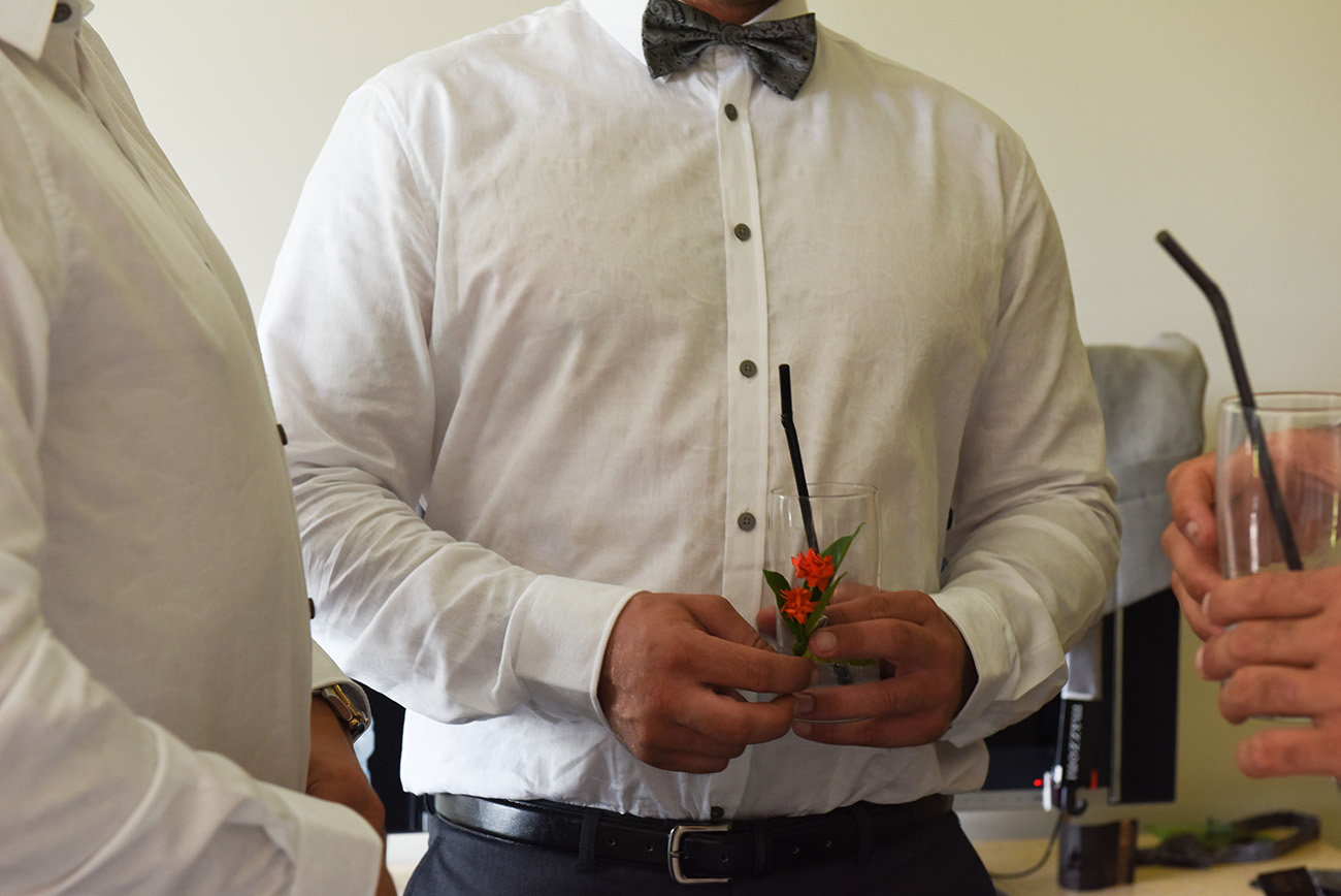 Half cropped of one of the groomsmen holding his cocktail and a flower