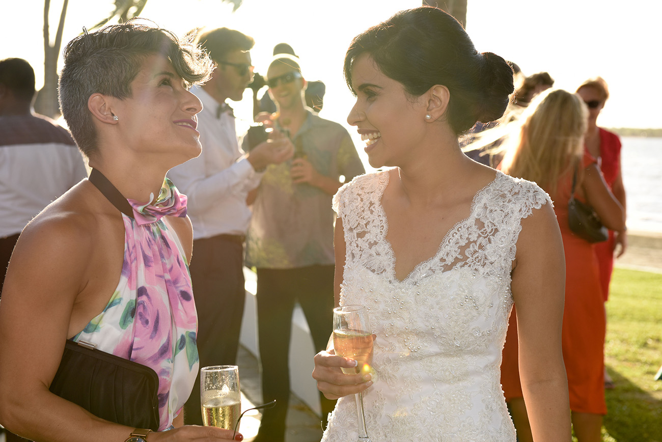 The bride laughing with a guest with a glass of bubbles in her hand