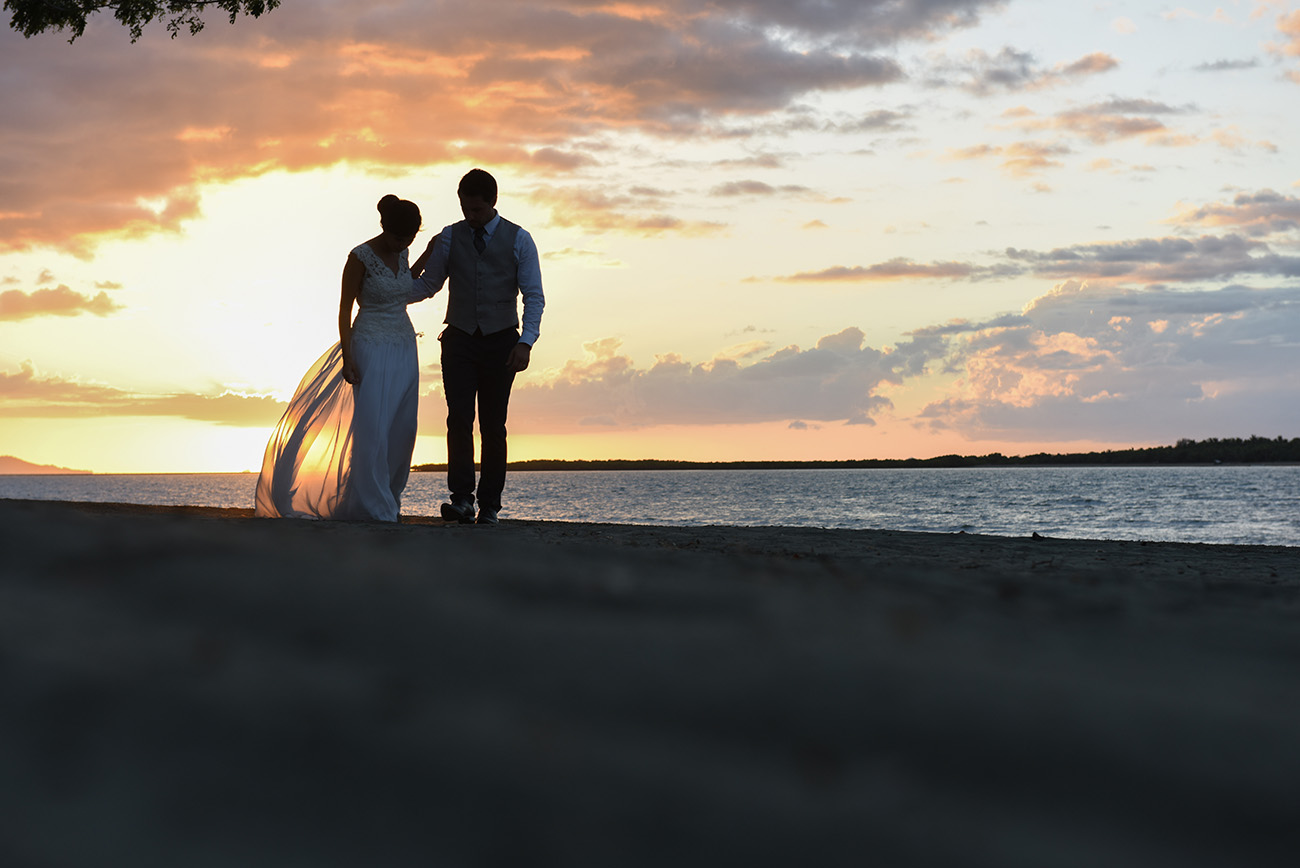 In front of an incredible sunset the bride and groom walking together