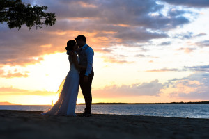 In front of an incredible sunset the bride and groom kissing