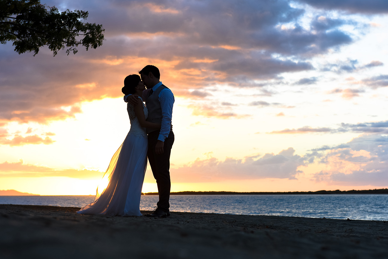 In front of an incredible sunset the bride and groom kissing