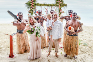 The couple pose with traditional Fijian dancers at their family Beach Wedding on Malolo Island, Plantation Island Resort, Fiji Wedding Photographer