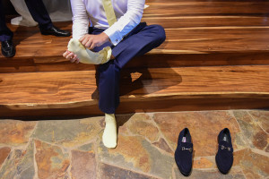 The groom is wearing yellow sock and puts his shoes on at his bure in paradise cove island resort in Fiji photographed by Anais Photography