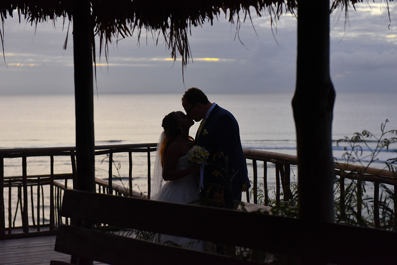 Silhouette of the bride and groom kissing with ocean is the background