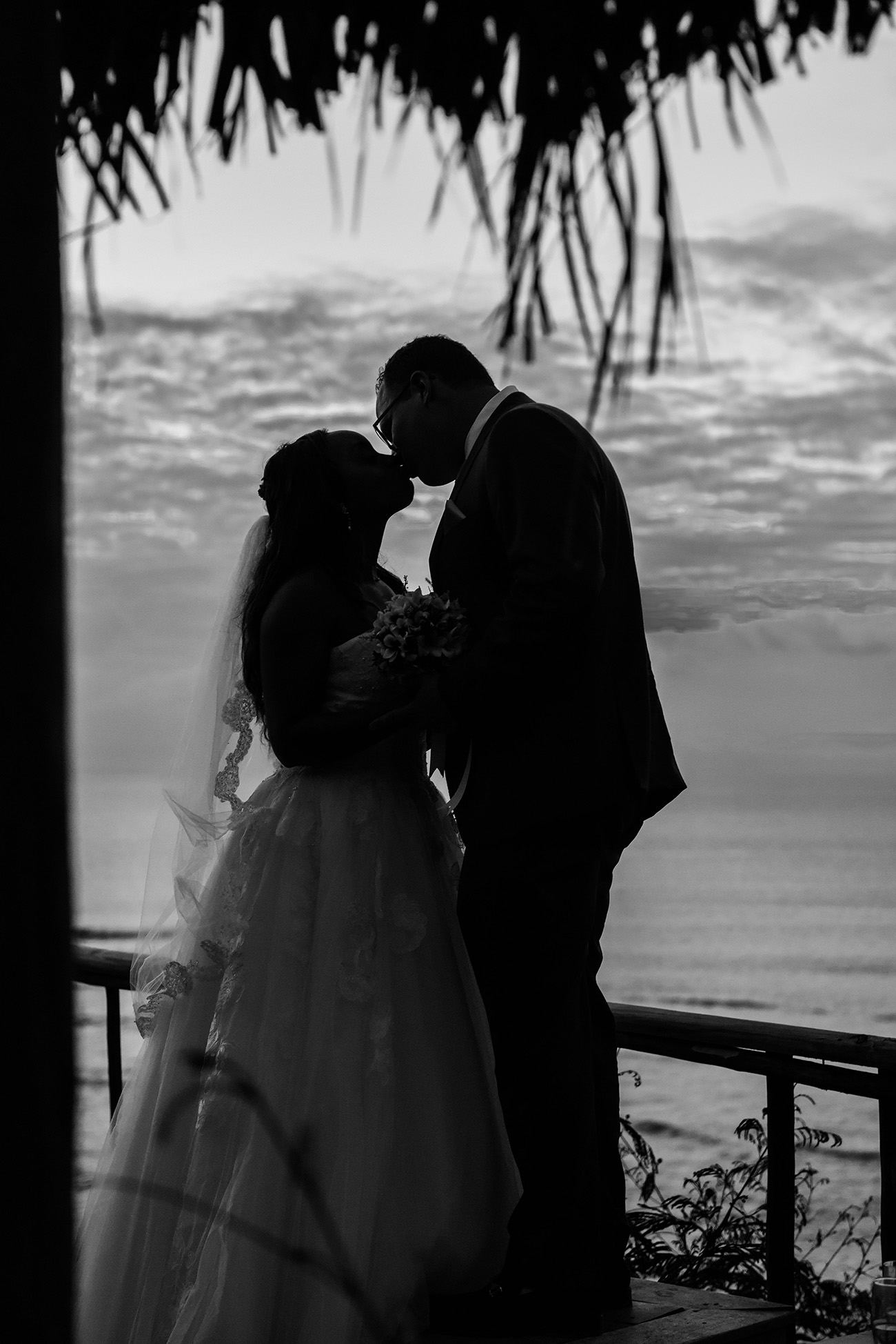 Silhouette of the bride and groom kissing black and white photograph. Ocean in the background. at Paradise Cove island resort in the Yasawas in Fiji photographed by Anais Photography