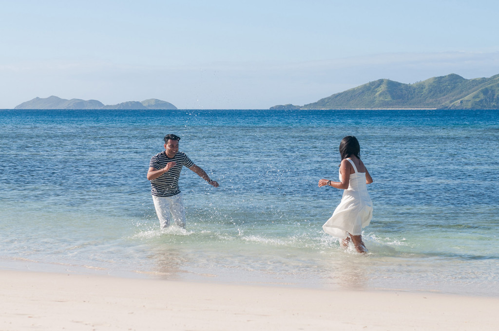 Couple playing in the pure blue ocean at Mana Island resort, Fiji by Anais Photography