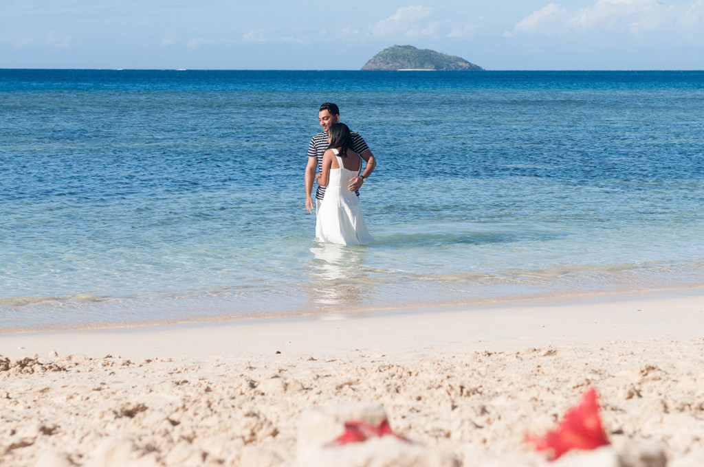 Couple cuddling in the sea by the beach at Mana Island resort, Fiji by Anais Photography