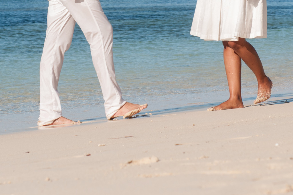 Legs of the couple walking on the white sandy beach at Mana Island resort, Fiji by Anais Photography