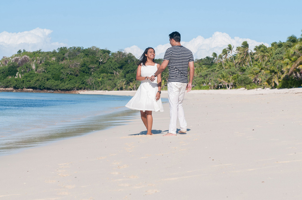 Couple walking along the white sand beach at Mana Island resort, Fiji by Anais Photography