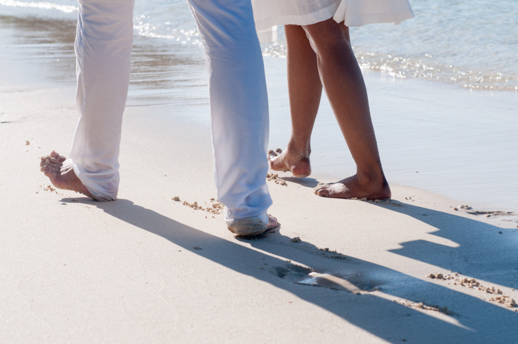 Couple's feet walking on the white sand at Mana Island resort, Fiji by Anais Photography