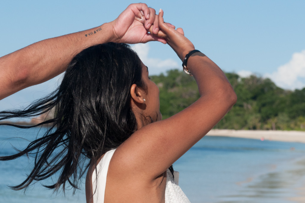 The fiancee is turning around herslef with hair in the air by the beach at Mana Island resort, Fiji by Anais Photography