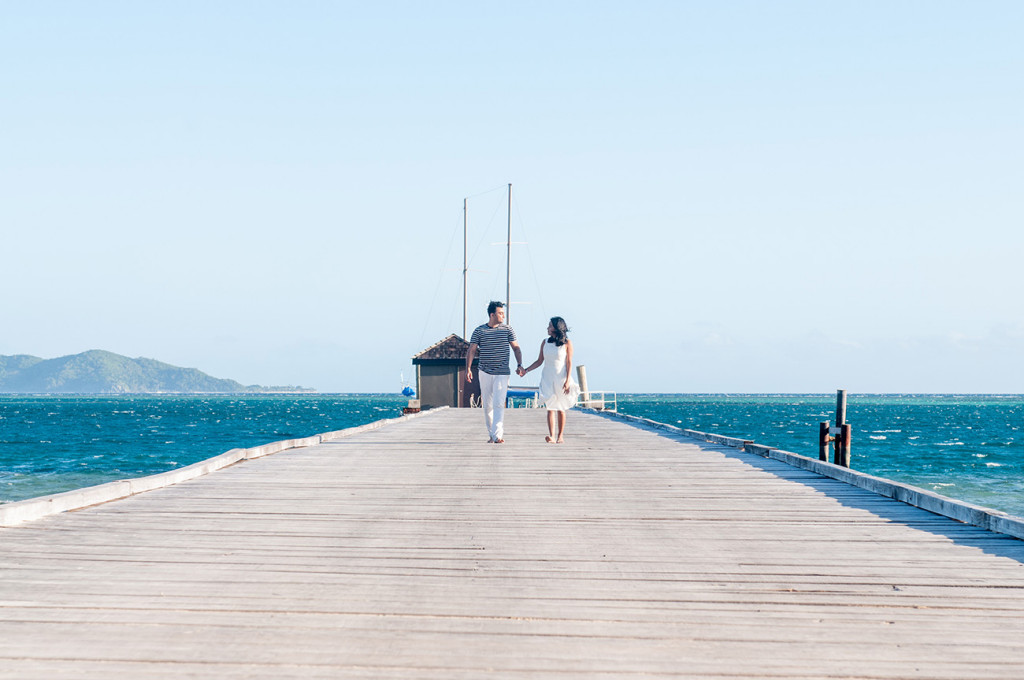 Couple walking on the jetty at Mana Island resort, Fiji by Anais Photography