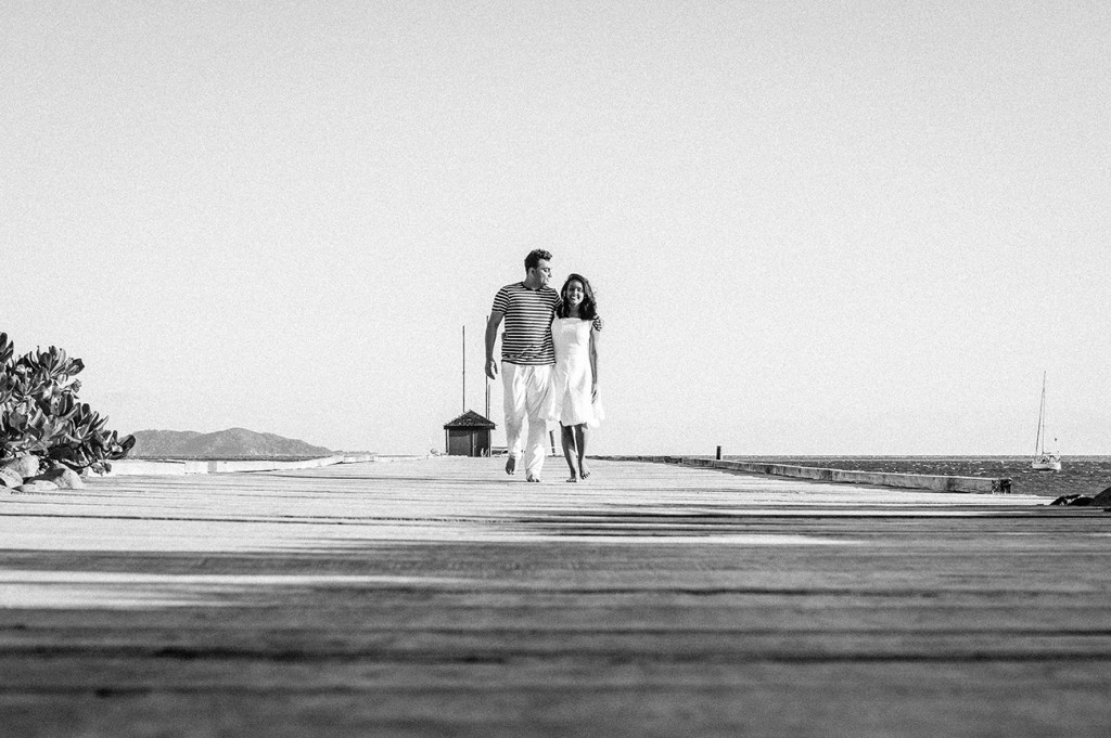 Couple walking on the jetty arms around each other at Mana Island resort, Fiji by Anais Photography