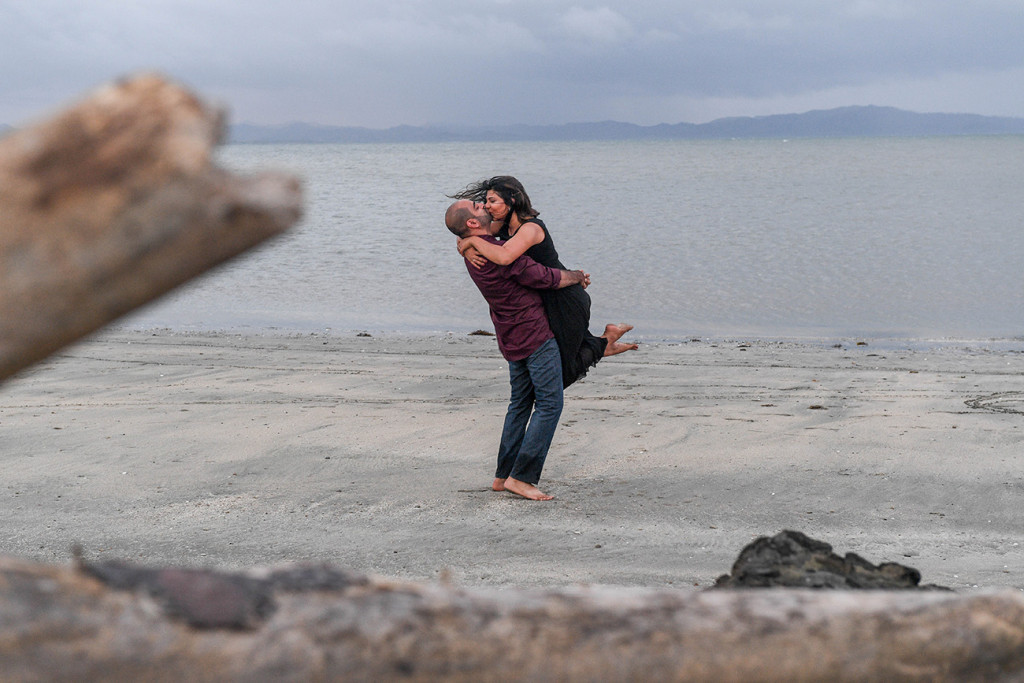 The wife is jumping on her husband's arm by the beach at the Sheraton Resort in Denerau Island in Fiji