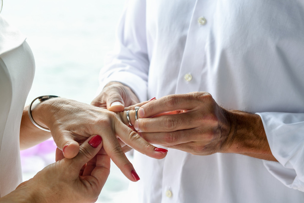 Husband is putting the ring on his wife's finger at the ceremony at Vomo Island resort, Fiji