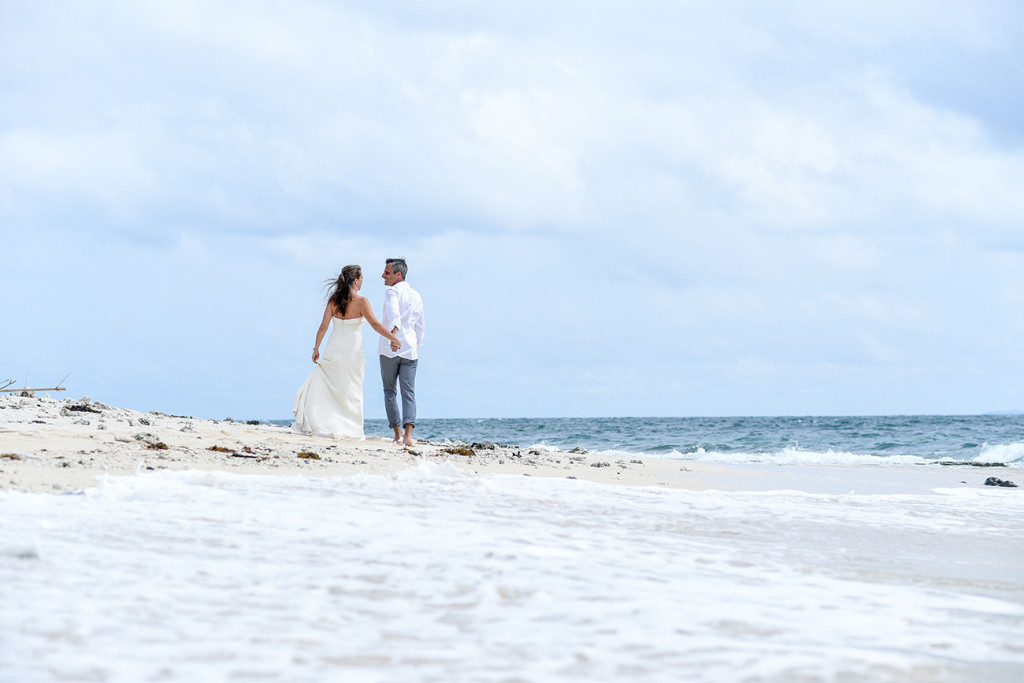 Couple holding hand and walking along the beach of Vomo Island resort, Fiji