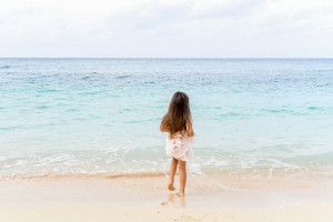Young girl walking toward the blue sea at Vomo Island resort, Fiji