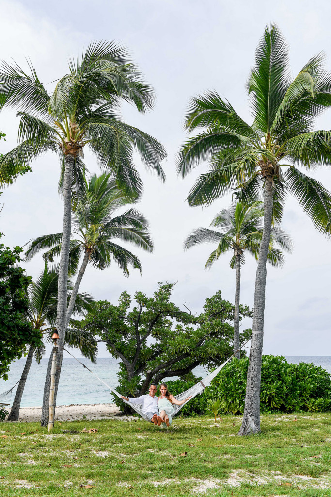 Couple on hammoc between two palm trees at Vomo Island resort, Fiji