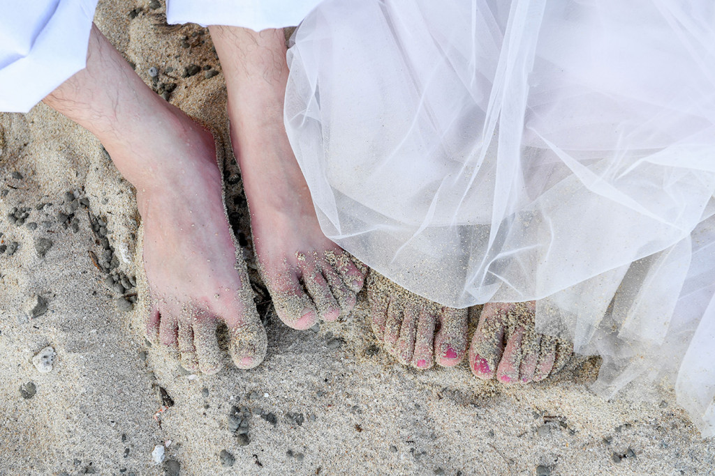 The couple's feet in the white sand Paradise Cove island resort, Fiji