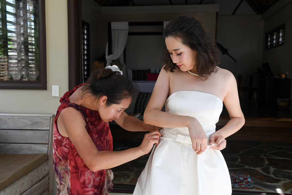 The bride is having help to put her wedding skirt on at Paradise cove island resort, Yasawas, Fiji