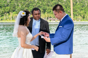 The groom is putting the ring on his wife's finger at Paradise cove island resort, Yasawas, Fiji