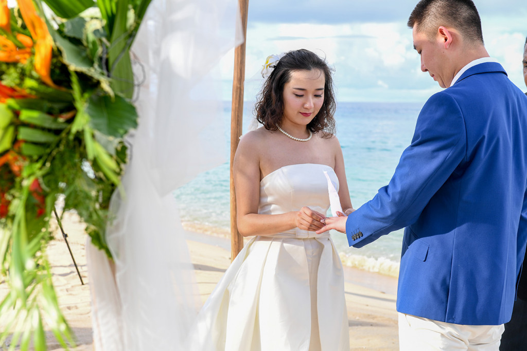 The bride is putting the ring on her husband's finger at Paradise cove island resort, Yasawas, Fiji