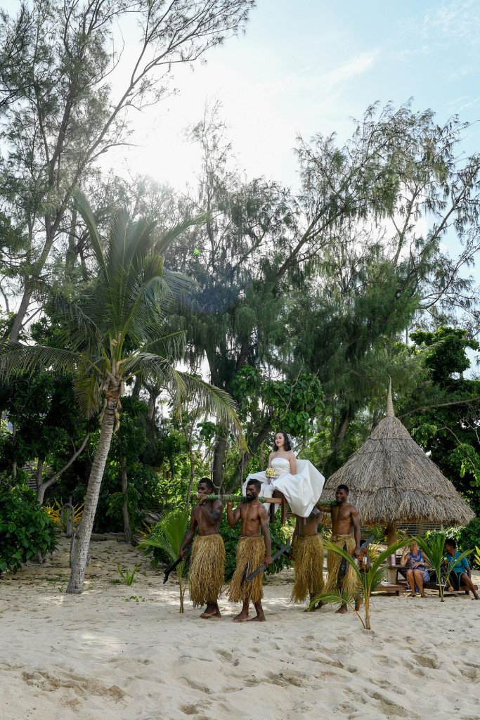 The bride is carried by the Fijian warriors to the beach at Paradise cove island resort, Yasawas, Fiji