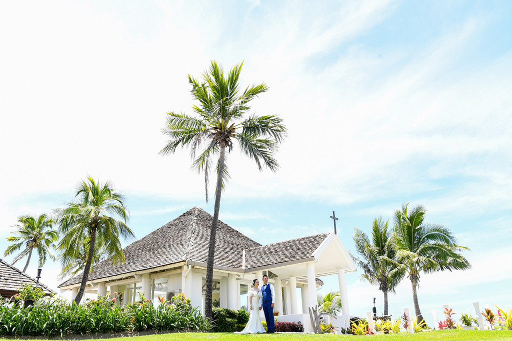 The bride and the groom are posing by the chapel at the sheraton beach in Denerau, Fiji