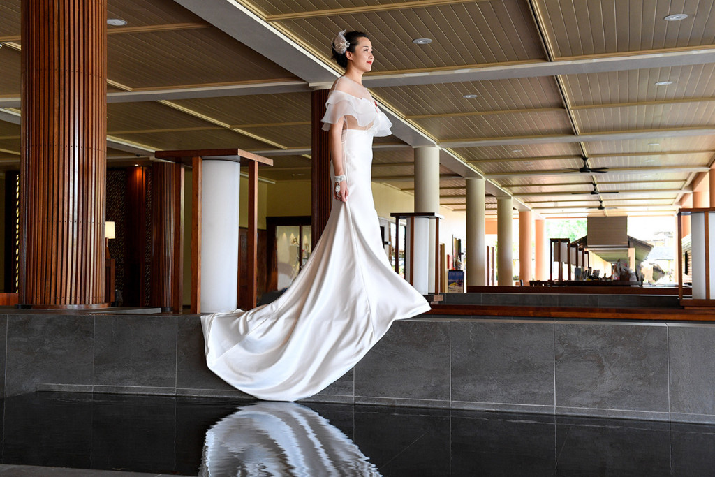 The bride is walking above a pond at the reception hall of the Sheraton resort in Denerau