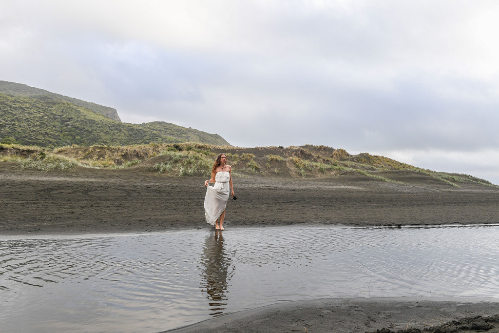 The beautiful bride dances on the black sand beach of Karekare New Zealand