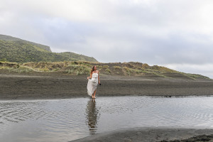 The beautiful bride dances on the black sand beach of Karekare New Zealand