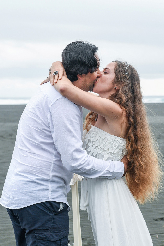 Bride and groom kiss on the shores of Karekare Beach Auckland New Zealand