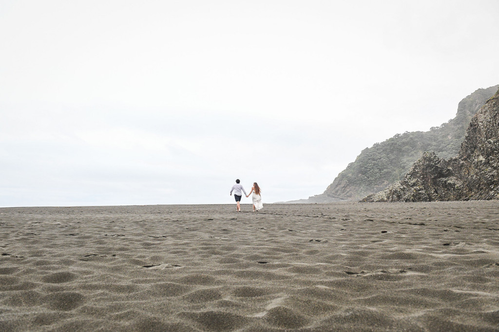 The eloped couple walk off into the horizon at Karekare Beach Auckland NZ