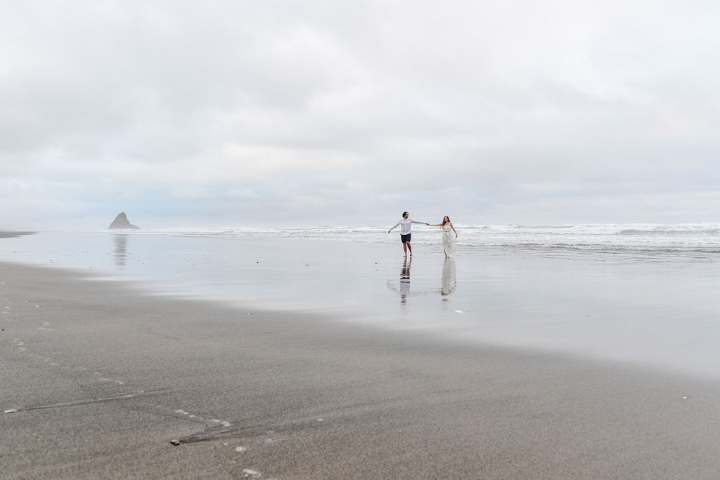 The newly married couple play in the sea at Karekare Beach NZ