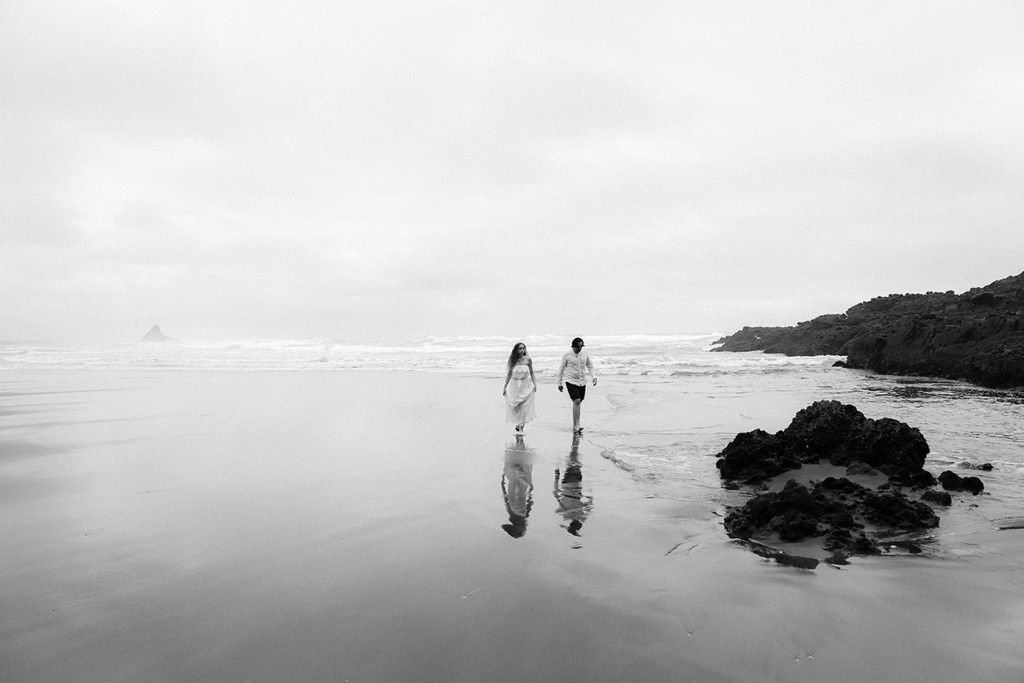 Black and white picture of newly eloped couple against stormy weather Karekare NZ