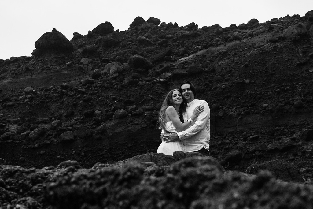Black and white photo of newly eloped couple cuddling in Karekare Auckland NZ