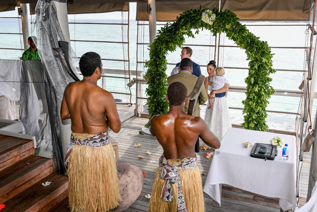 Fijian warriors watch on bride and groom at altar in family wedding Vomo Island Resort Fiji