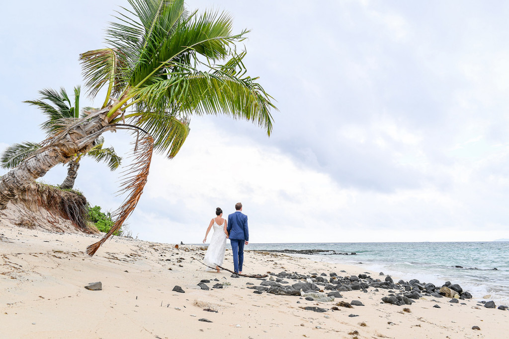 Couple walk by palm trees in Vomo Island Resort Fiji