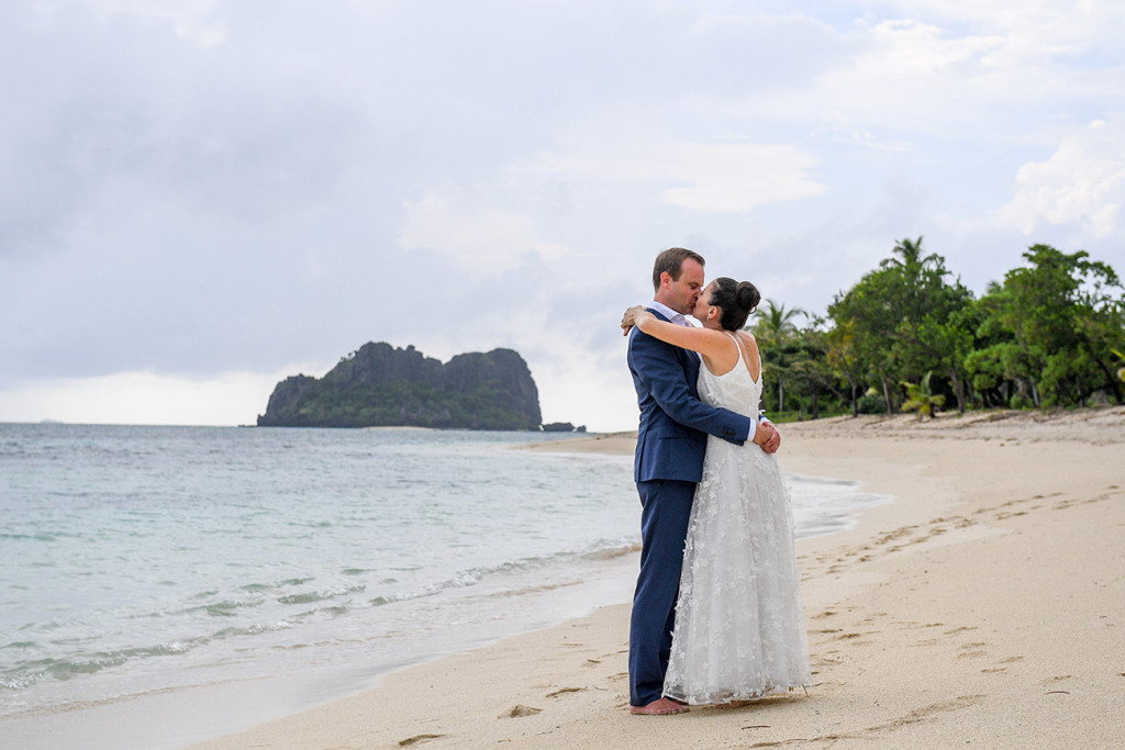 Married couple hug at beach in Vomo Island Resort Fiji wedding