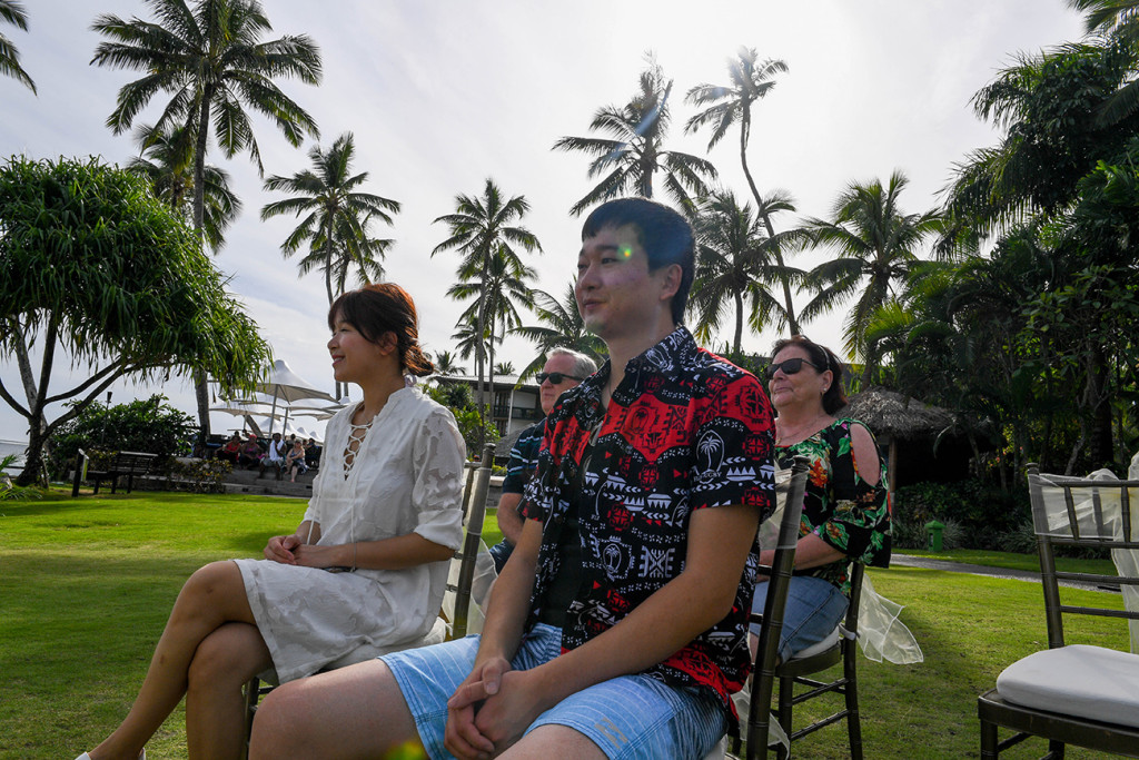 Wedding guests sit and watch against palm trees in Warwick Fiji